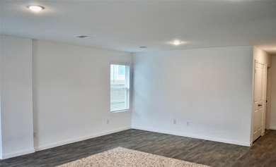 Living room view, plenty of natural lighting, laminate flooring, neutral beige color.