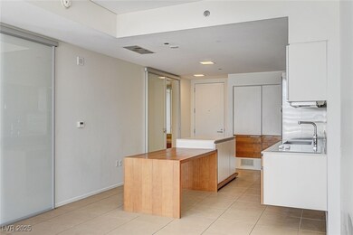 Kitchen with light tile patterned floors, white cabinetry, a center island, and butcher block countertops