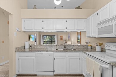 Kitchen featuring white appliances, light stone co