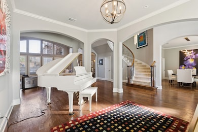 Entrance foyer featuring crown molding, a chandelier, stairs, and dark wood-style flooring