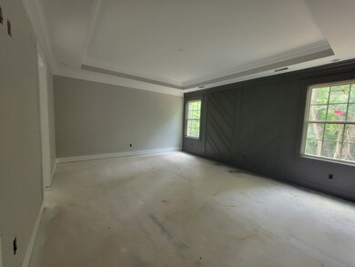 Master suite features accent wall with detailed trim work, tray ceiling, walk-in closet and full bathroom with dual vanities, garden tub, tile shower and tile floors