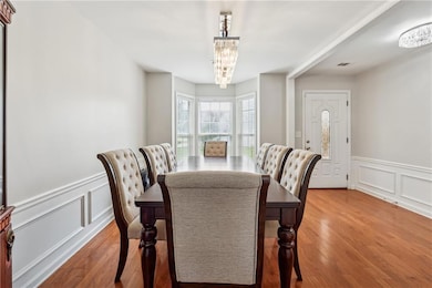 Dining room with a chandelier, a decorative wall, wood finished floors, and a wainscoted wall
