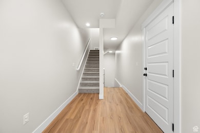 Corridor with stairs, light wood-type flooring, and recessed lighting