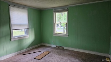 Spare room with baseboards, visible vents, and car