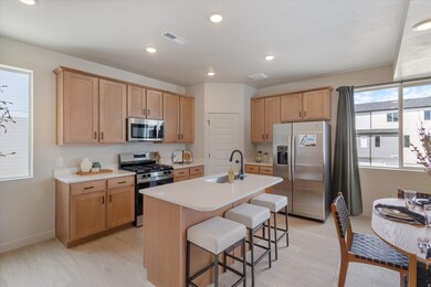 Kitchen featuring appliances with stainless steel finishes, recessed lighting, light brown cabinets, light countertops, and a kitchen breakfast bar
