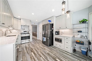 Kitchen with a sink, white cabinets, light wood-ty