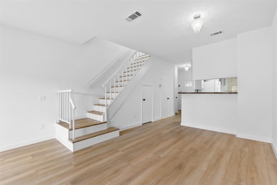 Unfurnished living room featuring light wood-type flooring and stairs