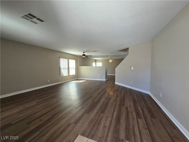 Spare room featuring baseboards and dark wood-style flooring