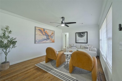 Sitting room featuring wood finished floors, ceiling fan, baseboards, and crown molding