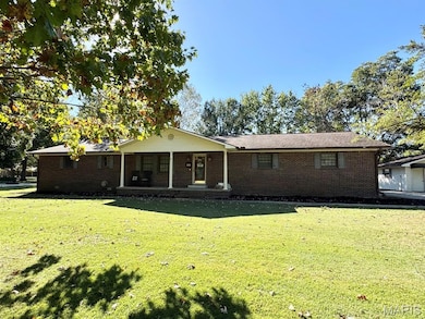 Ranch-style home featuring brick siding, covered porch, and a front lawn