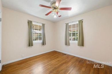 Unfurnished room featuring wood finished floors, plenty of natural light, and a ceiling fan