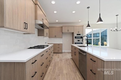 Kitchen featuring modern cabinets, decorative light fixtures, light wood-type flooring, recessed lighting, and backsplash