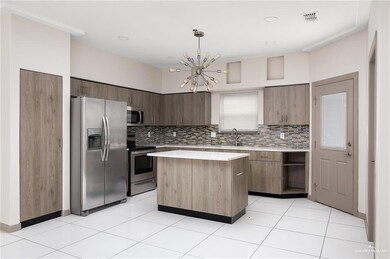 Kitchen with appliances with stainless steel finishes, light countertops, a center island, and modern cabinets
