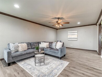 Living room with ceiling fan, ornamental molding, and light hardwood / wood-style floors