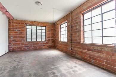 Spare room with brick wall and unfinished concrete flooring
