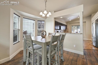 Dining space featuring baseboards, a chandelier, dark wood-style floors, and recessed lighting