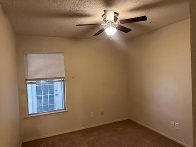 Empty room with dark colored carpet, a textured c