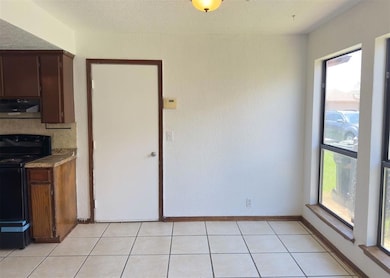 Unfurnished dining area with light tile patterned flooring and a textured ceiling