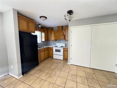 Kitchen featuring freestanding refrigerator, white range with electric cooktop, light tile patterned floors, backsplash, and light countertops
