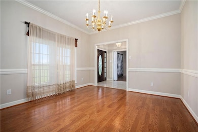 Spare room featuring ornamental molding, wood finished floors, and a chandelier