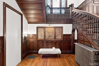 Stairway featuring wainscoting, wood finished floors, a decorative wall, and healthy amount of natural light