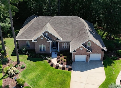 View of front of home with brick siding, concrete driveway, a garage, a front lawn, and a shingled roof