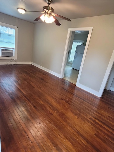 Empty room with dark wood-style floors, baseboard