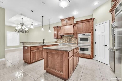 Kitchen with hanging light fixtures, a kitchen island, a tray ceiling, white double oven, and custom exhaust hood