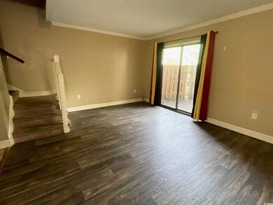 Unfurnished room featuring crown molding, dark wood-style flooring, baseboards, and stairway