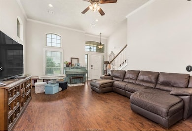 Living area with ornamental molding, dark wood finished floors, stairs, a towering ceiling, and recessed lighting