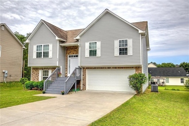 Raised ranch with brick siding, concrete driveway, a garage, cooling unit, and a front lawn