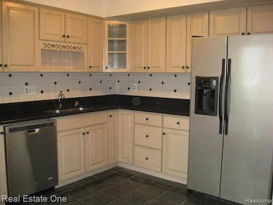 Kitchen with appliances with stainless steel finishes, tasteful backsplash, glass insert cabinets, and dark tile patterned flooring