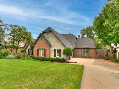 View of front of house with driveway, stone siding, a chimney, an attached garage, and brick siding