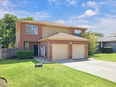 Traditional-style house featuring a garage, driveway, brick siding, and a shingled roof