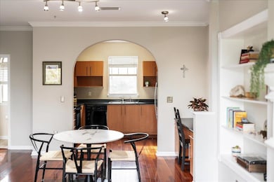 Kitchen featuring dark countertops, dark wood finished floors, ornamental molding, black appliances, and brown cabinets