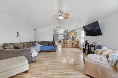 Living room featuring vaulted ceiling, light wood finished floors, and ceiling fan