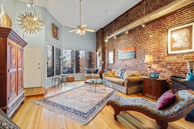 Living room with a towering ceiling, brick wall, l