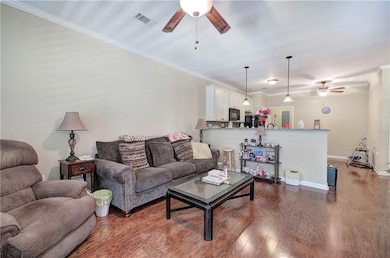 Living area featuring a ceiling fan, ornamental molding, wood finished floors, and baseboards