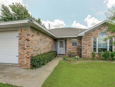 Ranch-style home with a front yard, a shingled roof, brick siding, and a garage