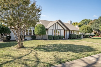 Tudor-style house with brick siding, a front yard, and a chimney