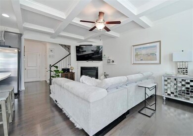 Living room with coffered ceiling, beamed ceiling, wood finished floors, a ceiling fan, and stairway