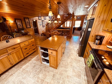 Kitchen featuring wooden walls, electric range, wooden ceiling, light stone counters, and freestanding refrigerator
