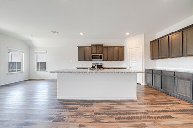 Kitchen with an island with sink, dark wood-type flooring, and stainless steel appliances