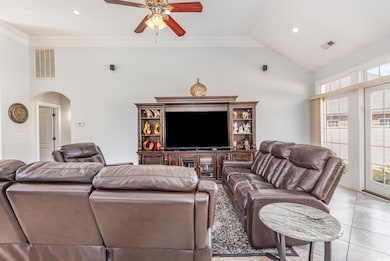 Tiled living room featuring a ceiling fan, arched walkways, crown molding, recessed lighting, and vaulted ceiling