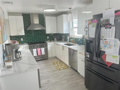 Kitchen with wall chimney range hood, a sink, stai
