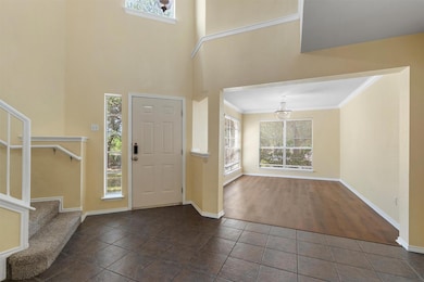 Foyer entrance featuring stairway, a high ceiling, ornamental molding, and dark tile patterned flooring