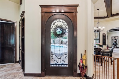 Foyer entrance featuring arched walkways, a chandelier, baseboards, and beamed ceiling