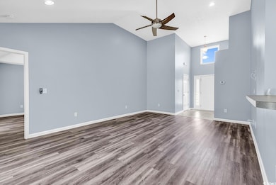 Unfurnished living room with ceiling fan, high vau