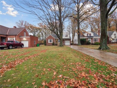 View of green lawn featuring concrete driveway and a residential view