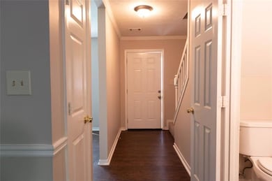 Hallway with dark wood-style flooring, crown molding, and baseboards